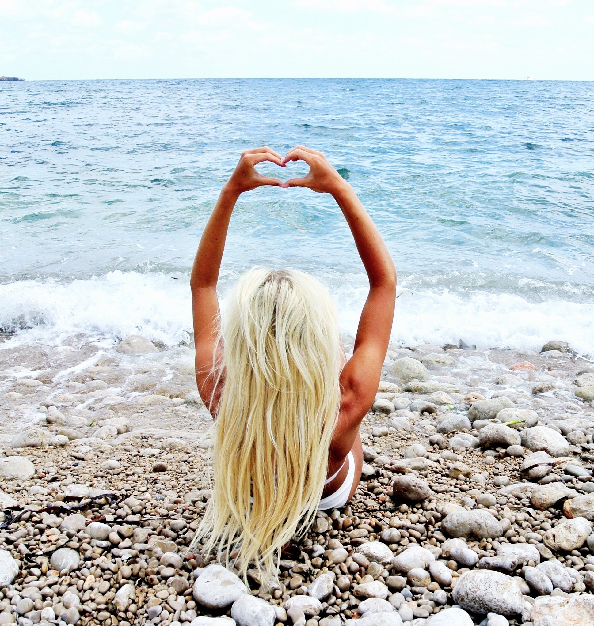 Молодая блондинка позирует в красном купальнике на пляже
