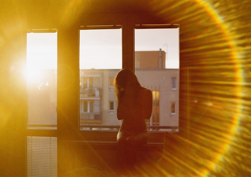 Яркое солнце светит в окна домов. Луч солнца в окне. Отражение солнца в окне. Солнечные блики на окне. Солнце в окне.