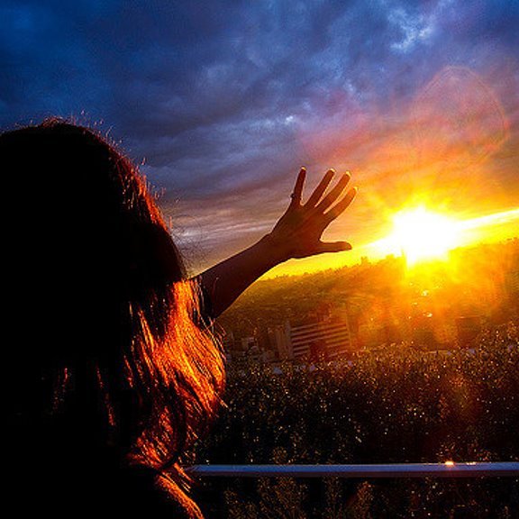 Девушка на закате держит солнце