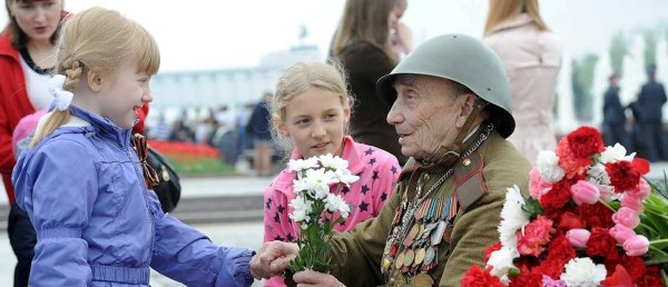 Мальчик дарит цветы ветерану