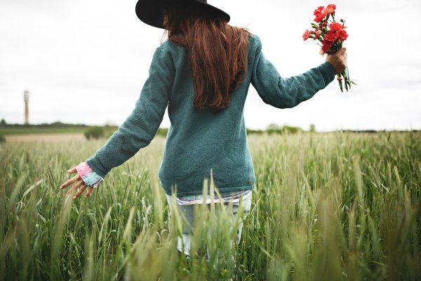 Девушка в поле с цветами со спины синее