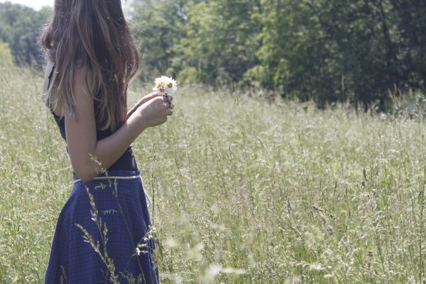 Девушка в поле с ромашками со спины