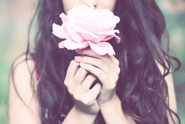 Девушка закрывает лицо цветами