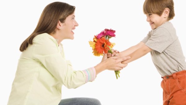 Мальчик дарит цветы маме
