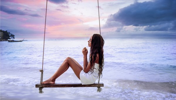 Девушка на качелях на берегу моря