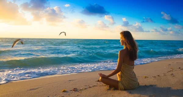 Девушка медитирует на берегу