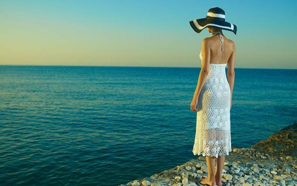 Женщина в шляпе на пляже в платье