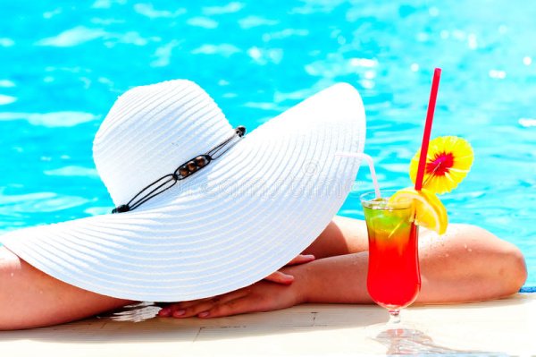 Баба на пляжу в шляпе с коктейлем