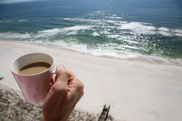 Чашка кофе в руке на фоне моря