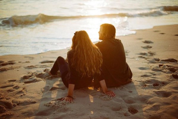 Парень с девушкой сидят на берегу моря