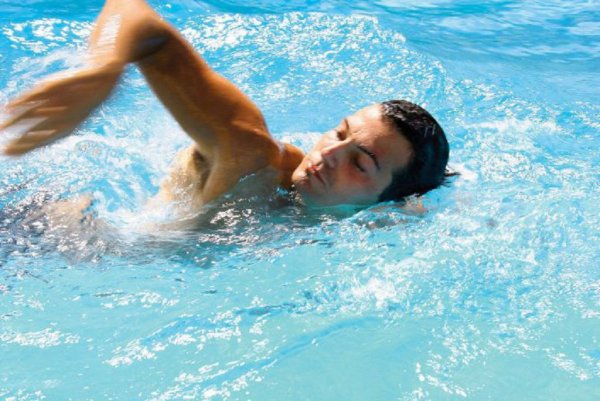 Мужчина плавает в бассейне