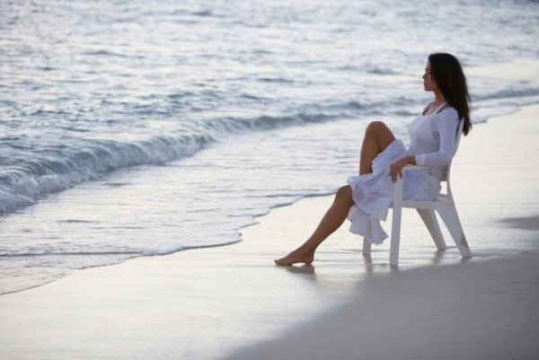 Женщина сидит на берегу