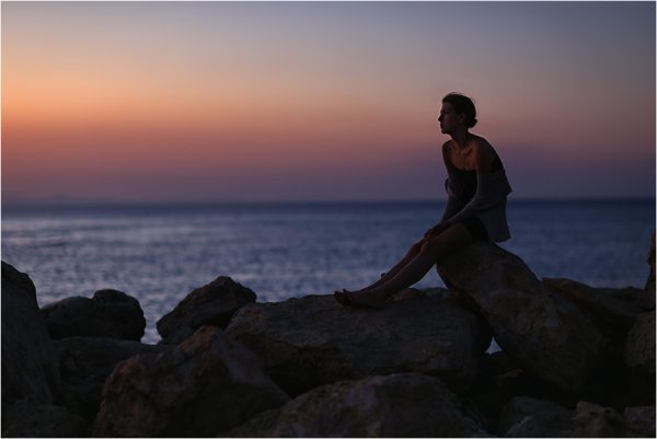 Девушка сидит на Камне у моря