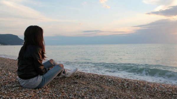 Девушка сидит у моря спиной