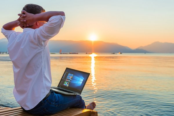 Мужчина на берегу моря с ноутбуком