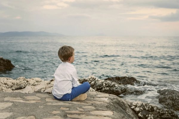 Мальчик сидит на берегу