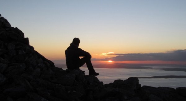 Человек сидит на берегу моря