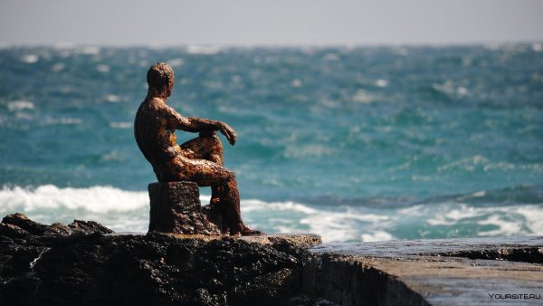 Девушка в платье на берегу моря сидит