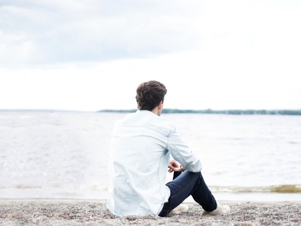 Человек сидит на лавочке у океана