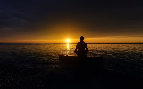 Человек сидит на берегу моря