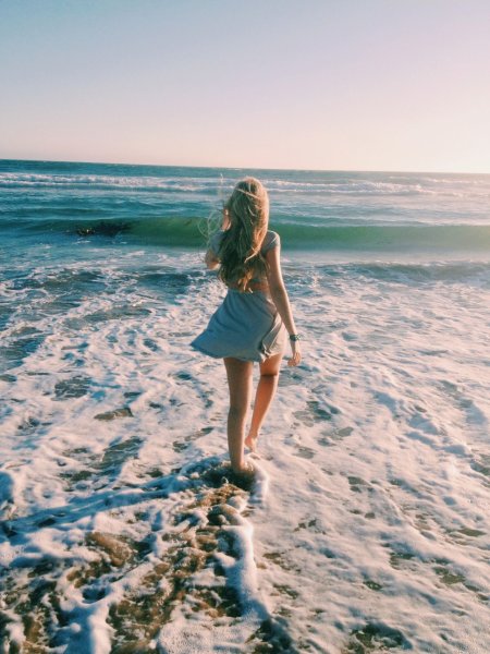 Девочка сидит на берегу моря