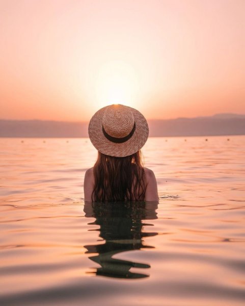 Блондинка в шляпе на море со спины