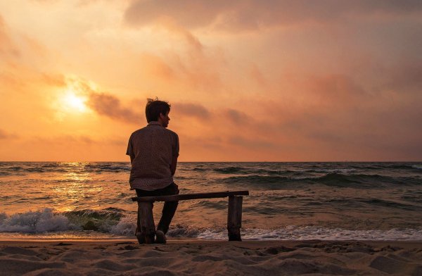 Одинокий человек на берегу моря на скамейке