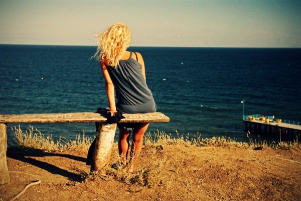 Девушка сидит на берегу моря