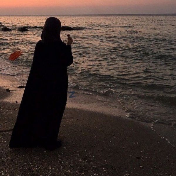 Мусульманка молится у моря на закате
