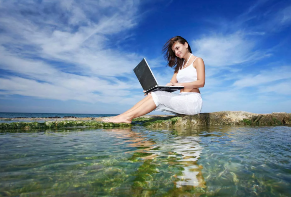 Мужчина на берегу моря с ноутбуком