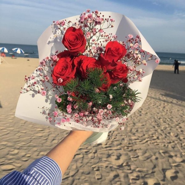 Мужчина дарит цветы женщине на берегу моря