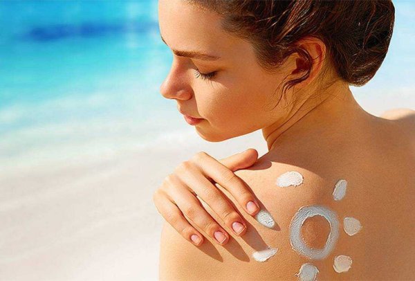 Девушка мажется солнцезащитным кремом