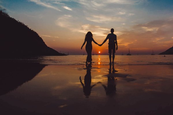 Пара держится за руки на закате