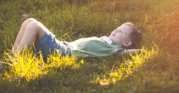 Мальчик лежит на траве