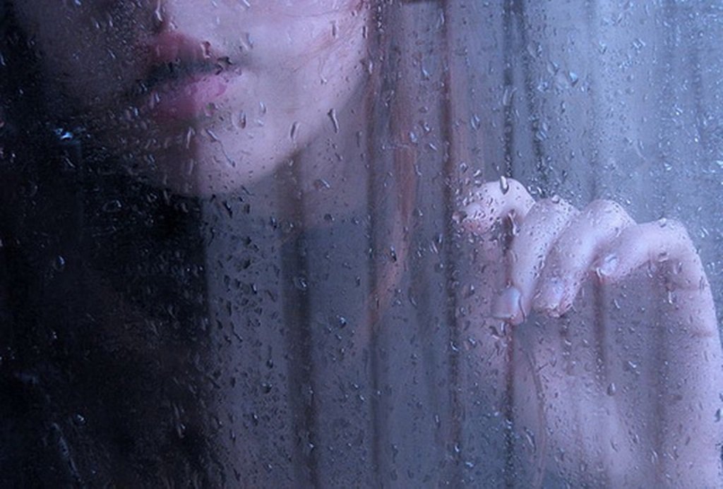 Юная девушка в нарядном платье плачет под дождем на темно студийном фоне