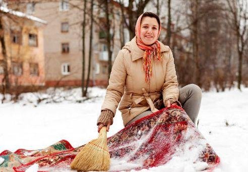 Женщина встряхивает ковёр