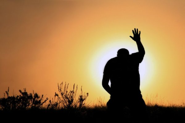 Человек молится на коленях