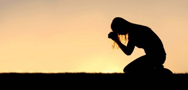 Человек молится на коленях