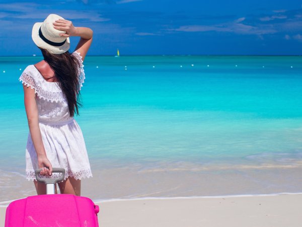 Девушка с чемоданом на пляже