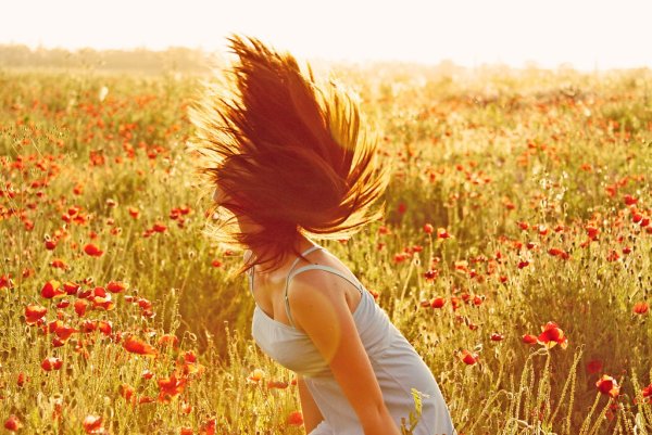 Рыжая девушка в поле со спины