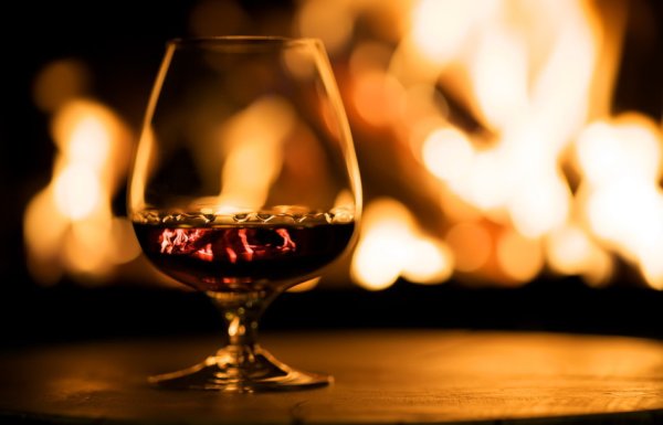 У камина с бокалом коньяка