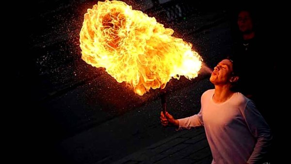 Человек выдувает огонь