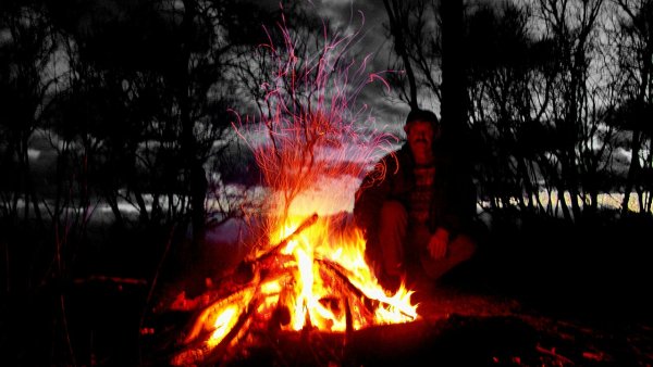 Парень зимой у костра