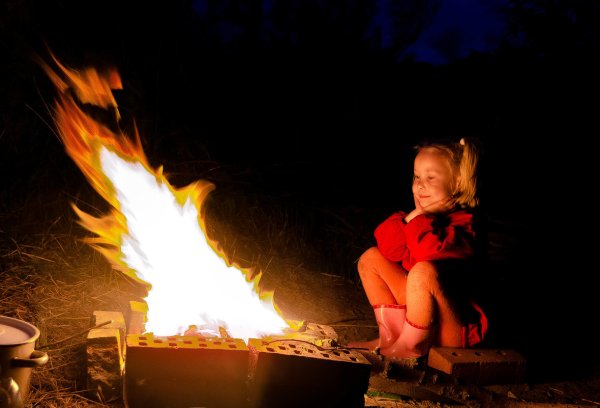 Девушка сидит у костра