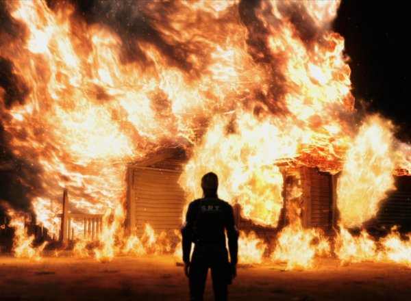 Человек на фоне горящего дома