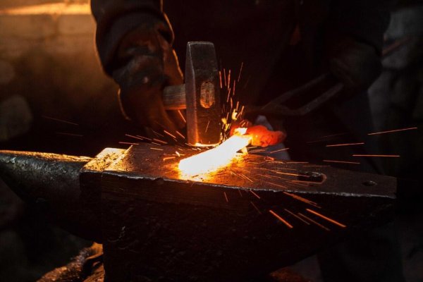 Кузнец в кузнице кует железо