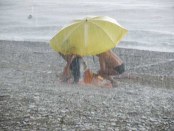 Под зонтом на пляже под дождем