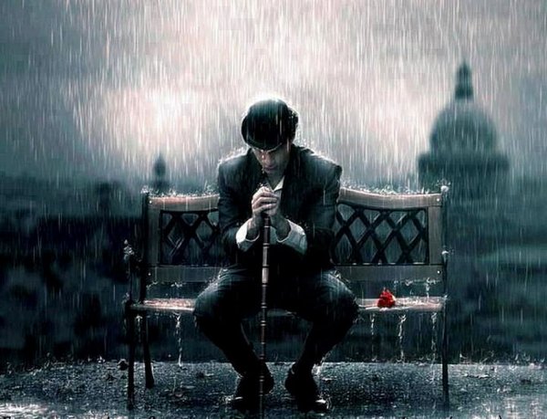 Парень сидит под дождем