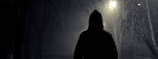 Мужчина в капюшоне в темноте