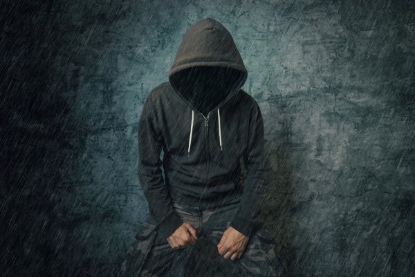 Человек в капюшоне сидит